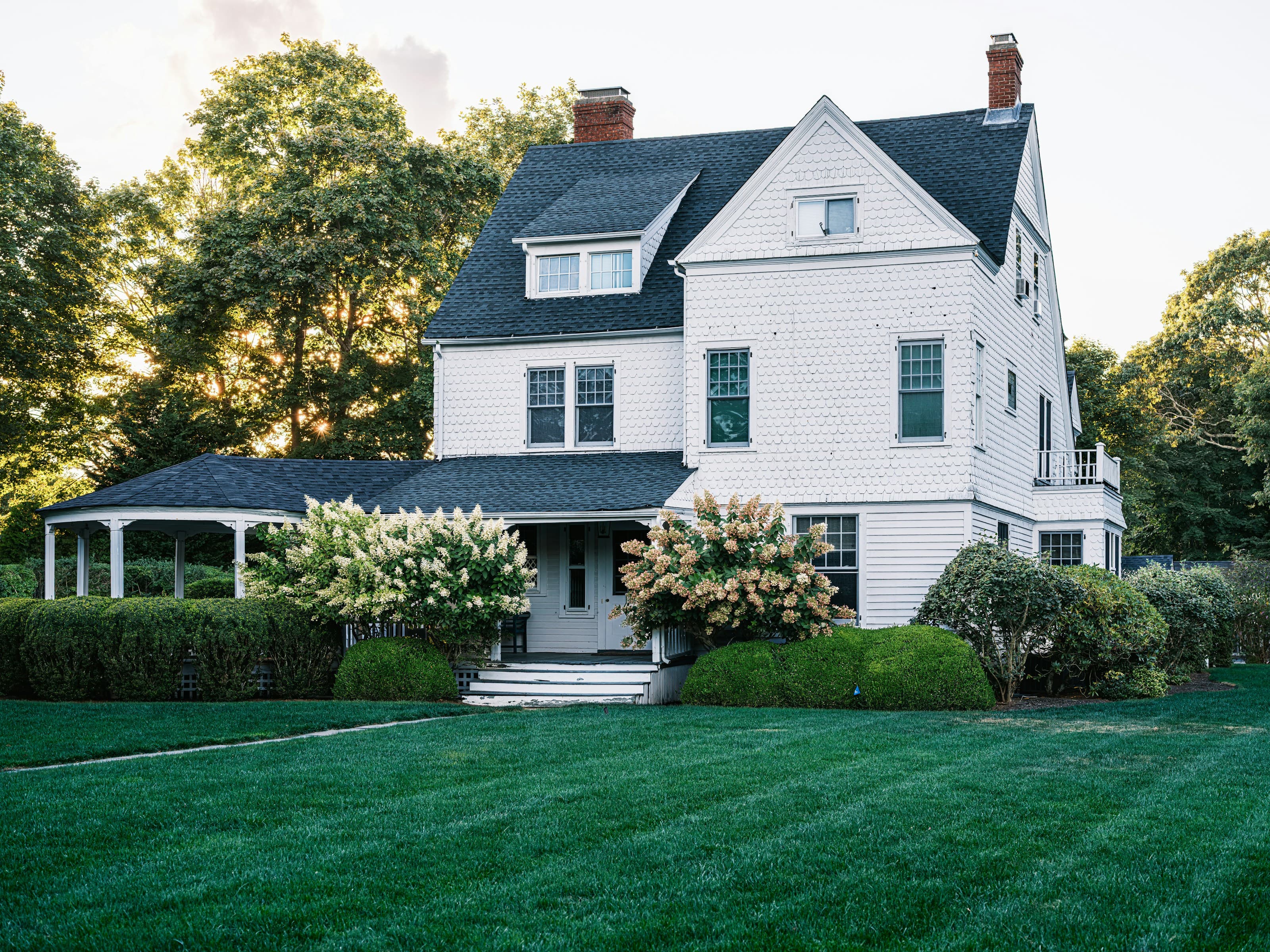 White two-story farmhouse with a charcoal shingle roof