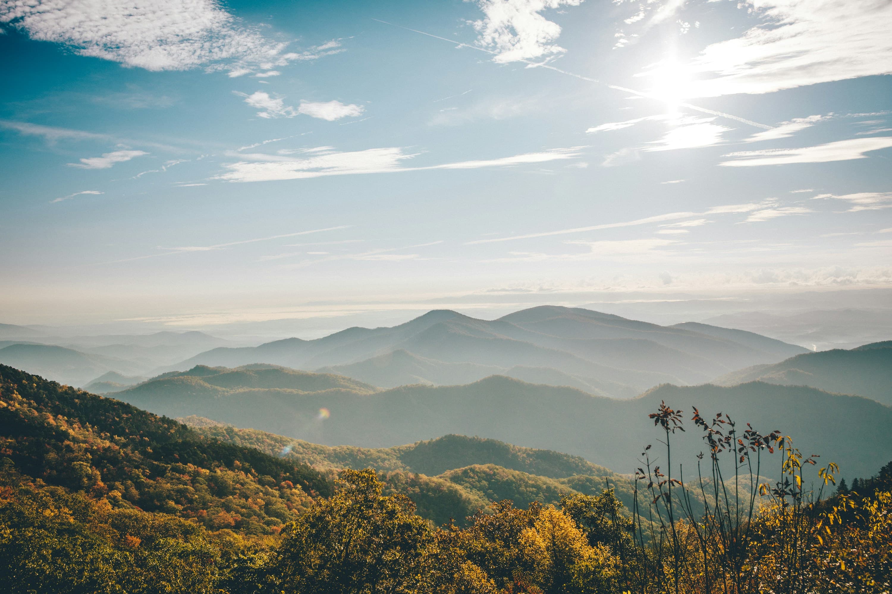 Layered mountain ridgelines at golden hour over autumn trees