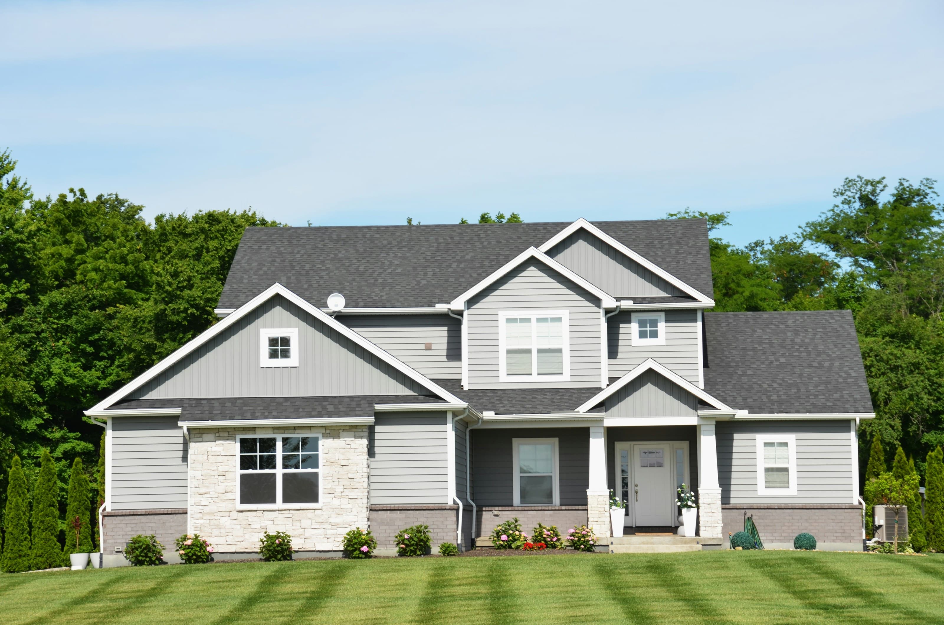 Gray two-story home with a dark shingle roof and white gable trim