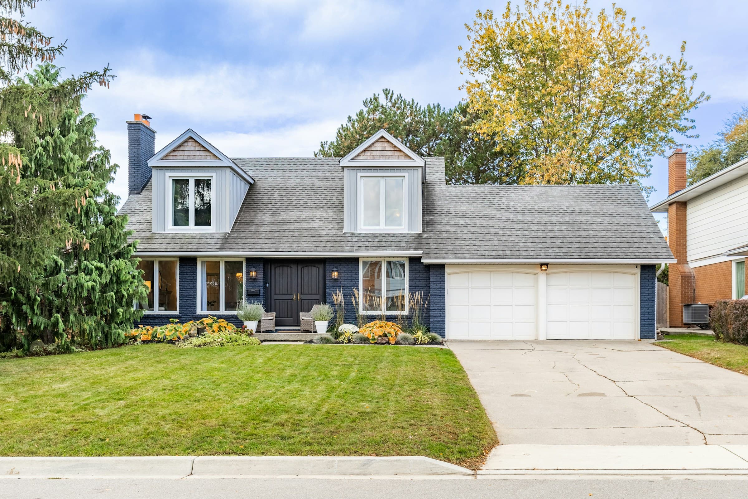 Blue brick home with two dormers and a gray shingle roof